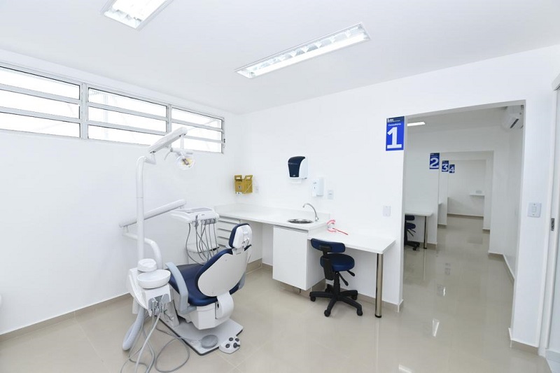 #PraCegoVer: Na foto há uma sala de dentista, com cadeiras e equipamentos odontológicos. É uma sala clara e bem iluminada, as paredes são brancas